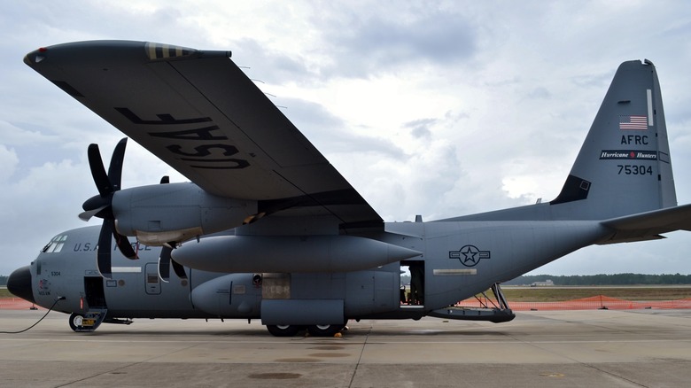 A gray WC-130J sits on the tarmac under a cloudy sky