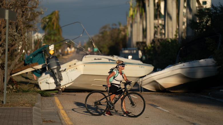 Woman walking in front of Hurricane Ian damage
