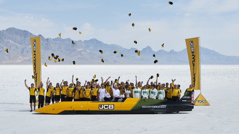 JCB Hydromax team members standing behind the hydrogen powered vehicle at the Bonneville Salt Flats and throwing their hats in the air in celebration