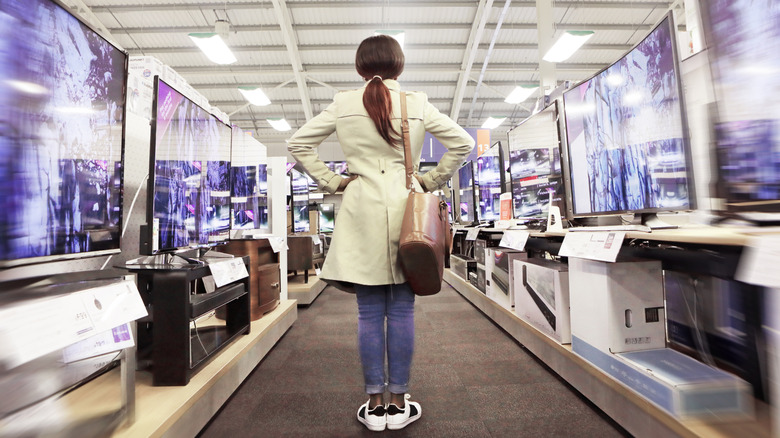 A woman standing in a TV aisle at an electronics store