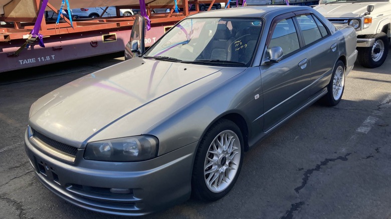 Silver 2000 Nissan Skyline R34 4-door parked with driver's door ajar