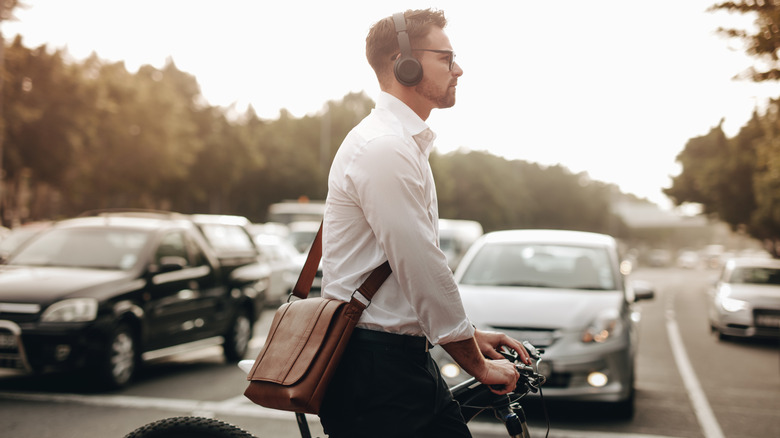 Man crossing road on bike while wearing over-hear headphones.