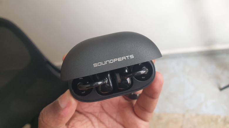 Person holding an open case of soundpeats clip-on earbuds.