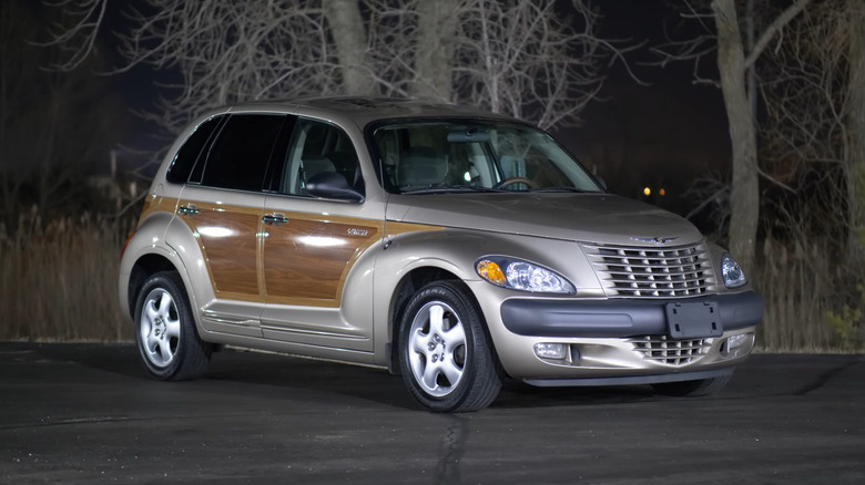 A gold Chrysler PT Cruiser with wood panel decals on the sides, front 3/4 view, nighttime