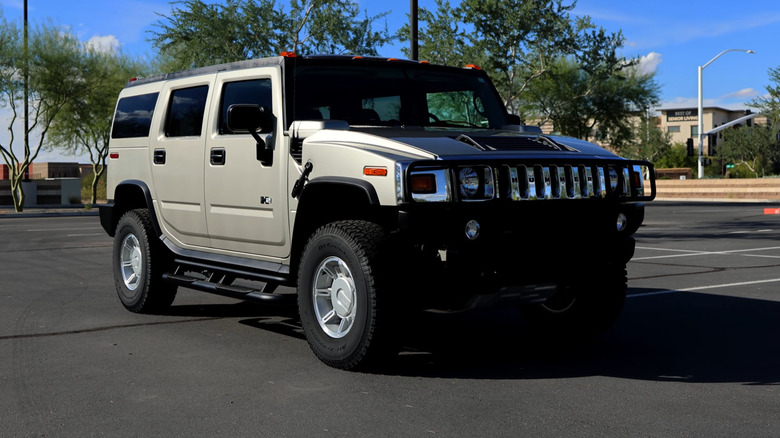 A gold Hummer H2 in a parking lot, front 3/4 view