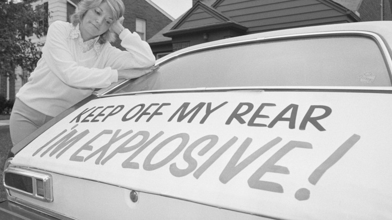 A Ford Pinto with a sign indicating its explosive potential.