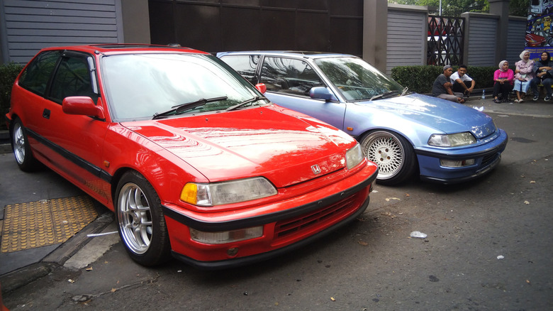 Two tuned 90s Honda Civics parked in a suburban setting.