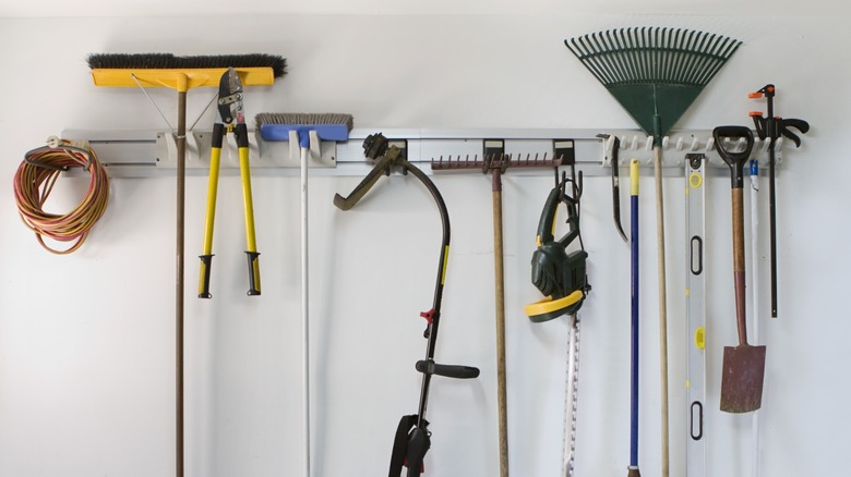garden tools and other equipment hanging on wall hooks