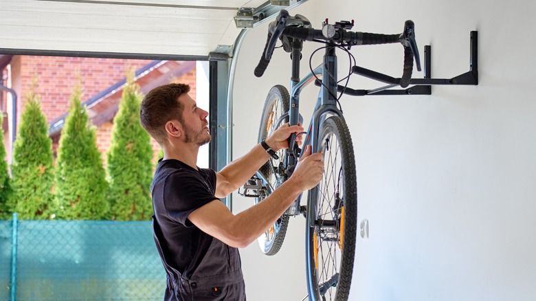 a person mounting a bike on a wall rack