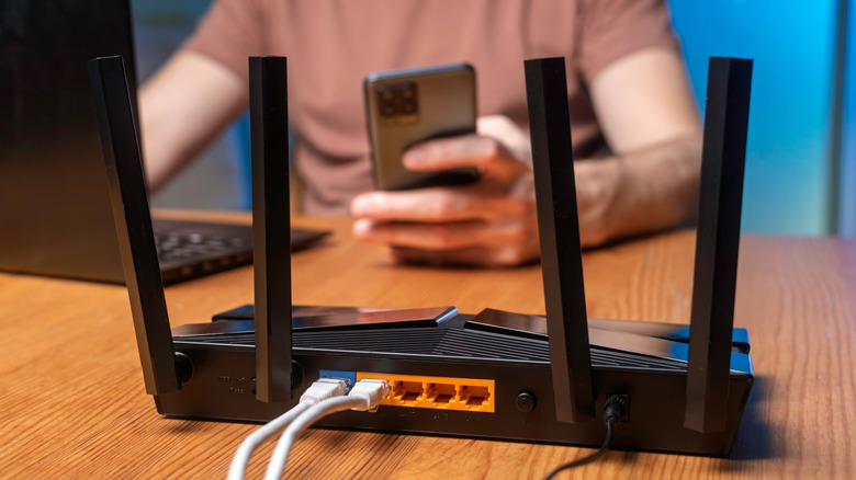 A Wi-Fi router with a person using a phone and laptop in the background