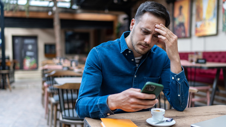 A worried person looking at his iPhone.