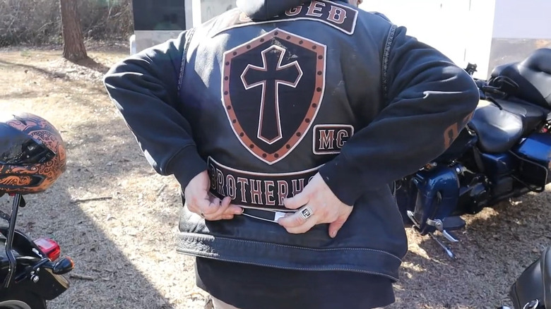 Biker showing where a pass through pin used to be hung on a cut (vest).