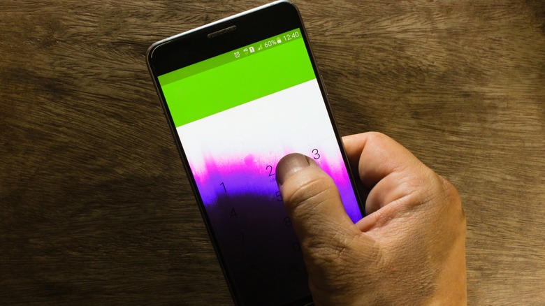 Thumb applying pressure on a purple-stained Android phone screen