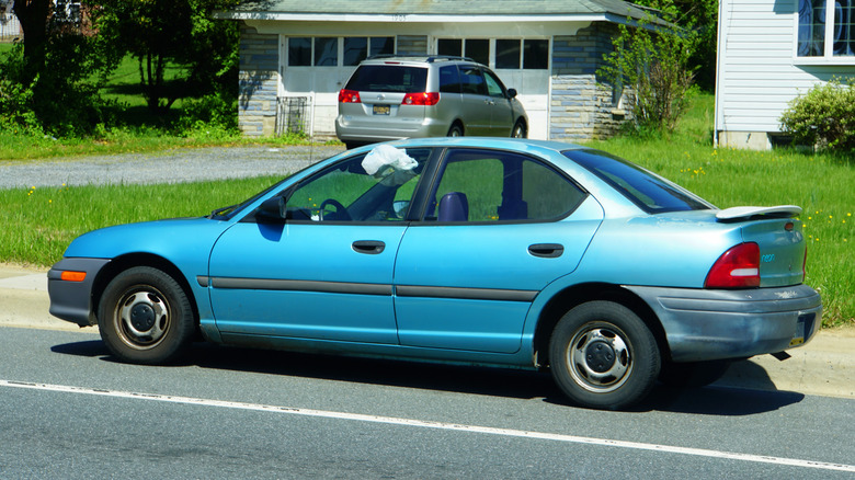 A broken and abandoned car on the road with white cloth stuck on the window to alert traffic
