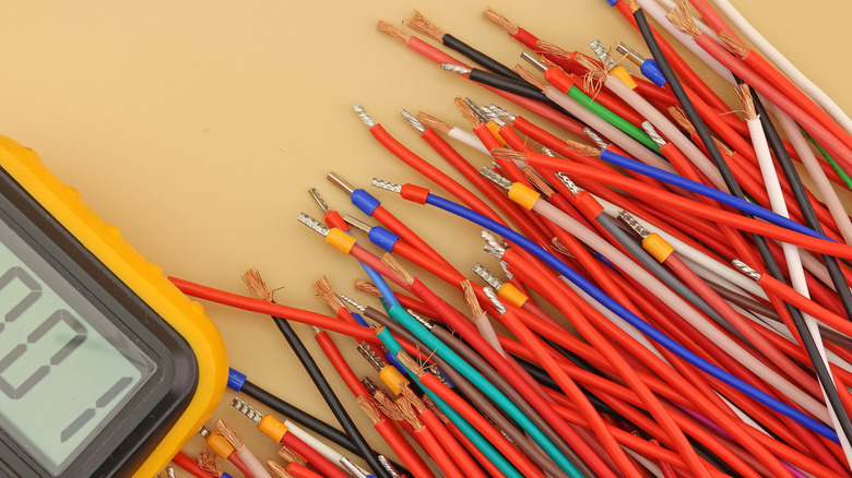 various copper wires of different colors sitting next to a yellow multi-meter