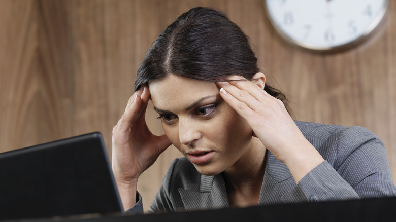 Person using laptop holding head