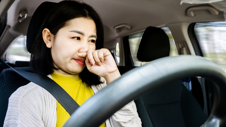woman covering her nose inside car
