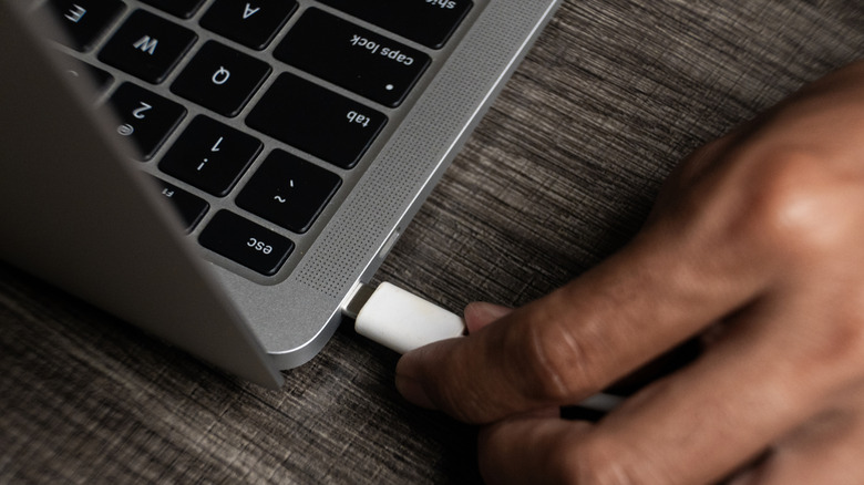 A hand plugging a USB-C cable into a laptop