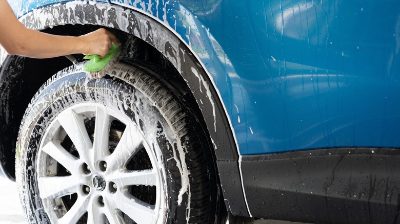 person cleaning a tire with lots of soap suds and a scrubber