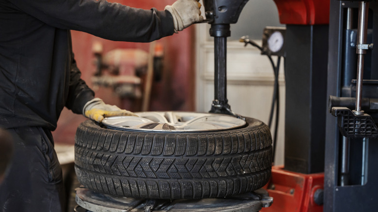 A man is fitting a tire using a tire press