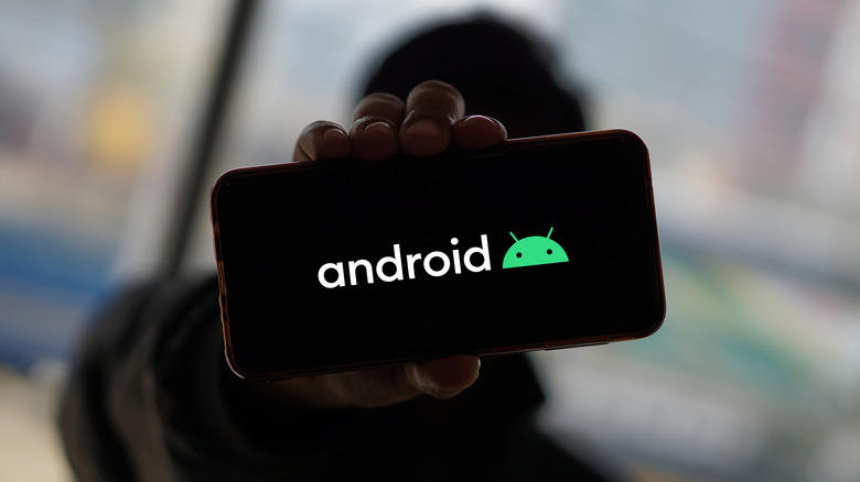 Hand holding smartphone with Android logo displayed