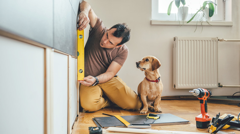 A man working on a home improvement project with his dog nearby