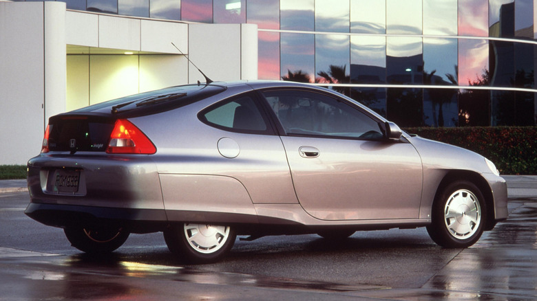 Rear 3/4 view of silver first-gen Honda Insight parked in front of a building