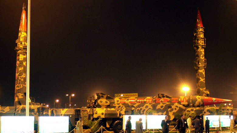 3D render of short-range tactical warheads mounted on MLRS wheeled platform with Pakistan flag in background