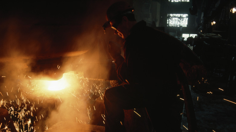 Steel worker with goggles on working in a production plant.