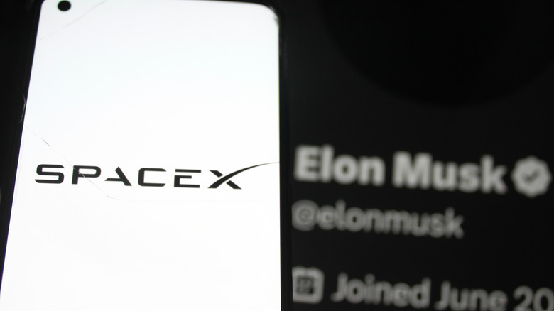 SpaceX logo displayed on a smartphone screen. With SpaceX CEO Elon Musk X profile photo in the background.