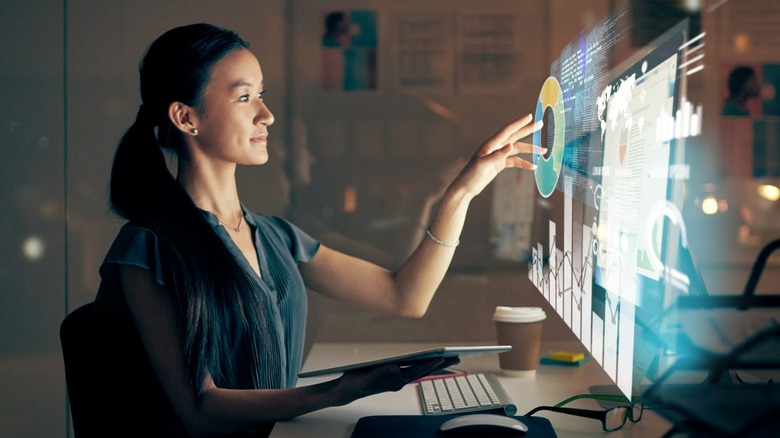 woman reaching out with her hand to control a futuristic touchscreen