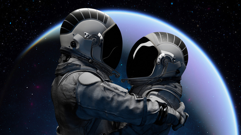 Astronauts embracing in space.