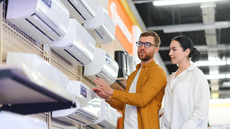 A couple browsing split air conditioners on display at a home appliance showroom