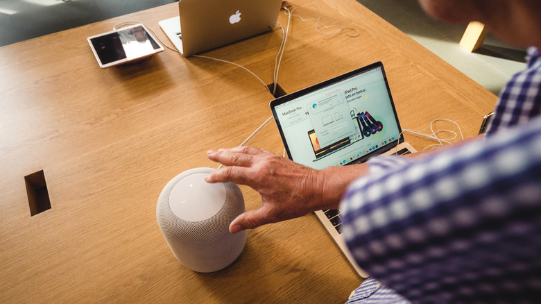 Man using an Apple HomePod with other Apple products.