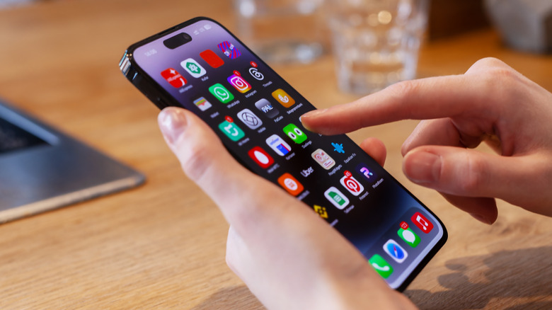Person using an iPhone 16 on the home screen