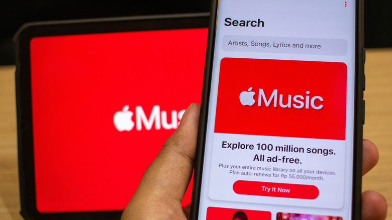 Apple Music displayed on smartphone with tablet with Apple Music logo in the background