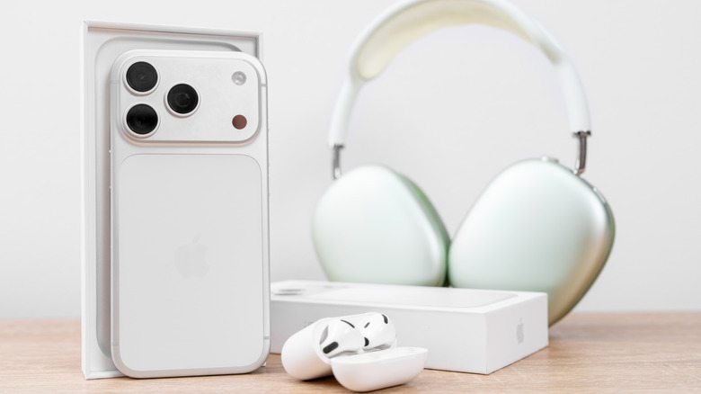 A picture of an iPhone 17 Pro, AirPods Max 2, and AirPods 3 on a wooden tabletop