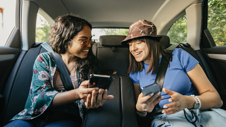 two teens in car with iPhones