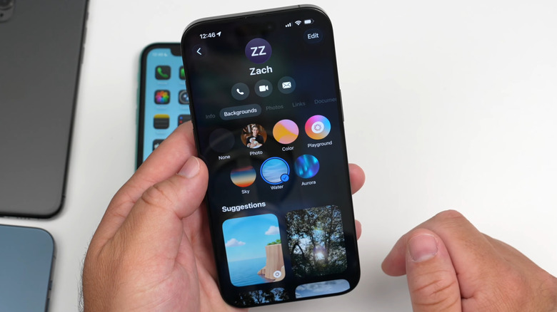iPhone in hand showing chat background feature in Messages app