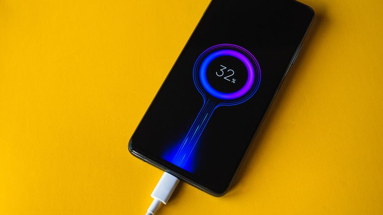 A phone being chargd using a cable with the charging percentage displayed on the screen