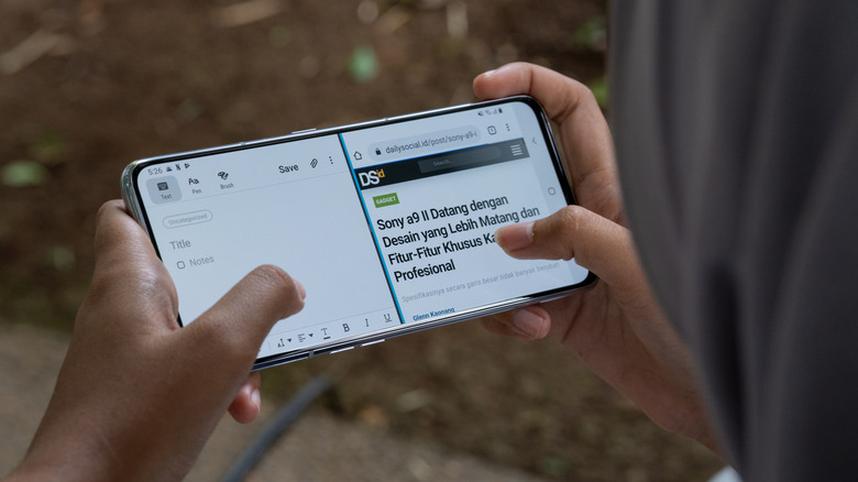 A person using an Android phone in split-screen multitasking mode