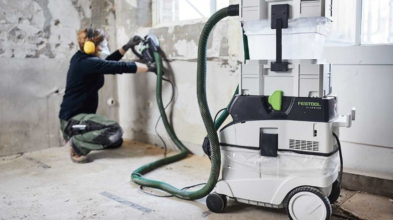 Person sanding paint from concrete with dust extractor