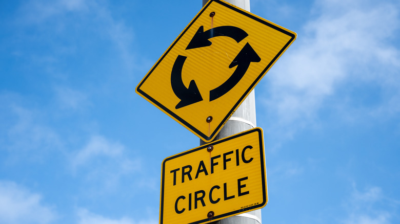 Close shot of road sign denoting a traffic circle with roundabout symbol