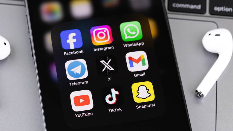 Smartphone kept on a laptop displaying various social media apps
