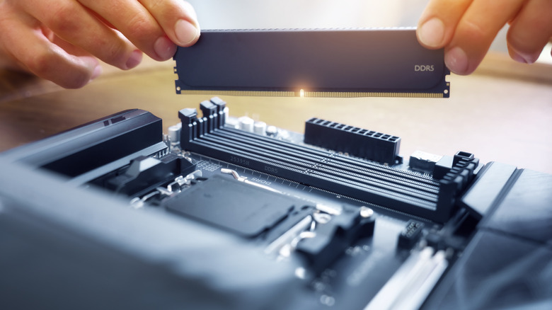 A person installing an unbranded DDR5 RAM stick on a motherboard