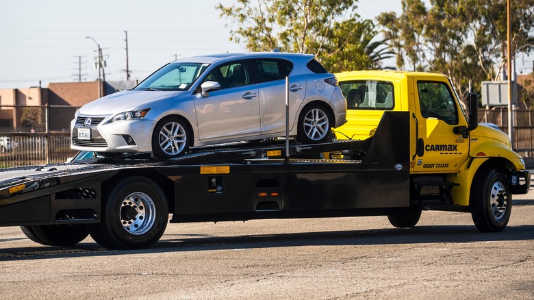 A silver Lexus on the back of a CarMax transport truck.