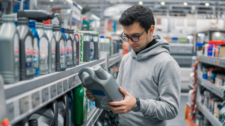 A customer examines a bottle of oil in an auto parts store