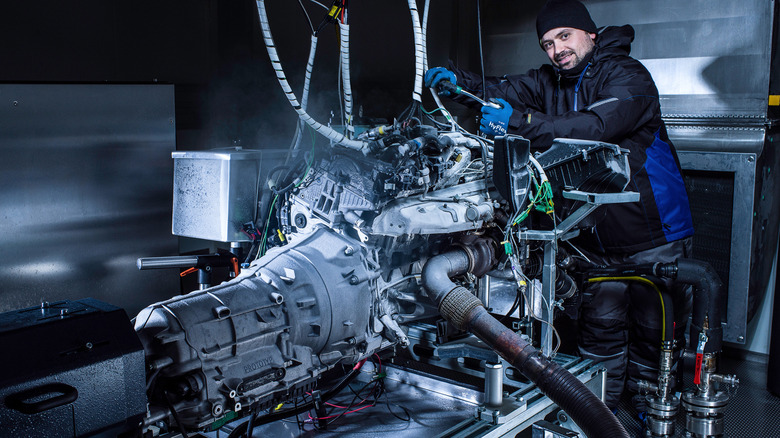 An automotive factory worker with a diesel engine and transmission on a test bench at the BMW engine plant