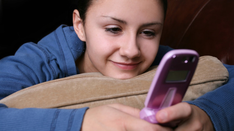 A teenage girl texting on a flip phone