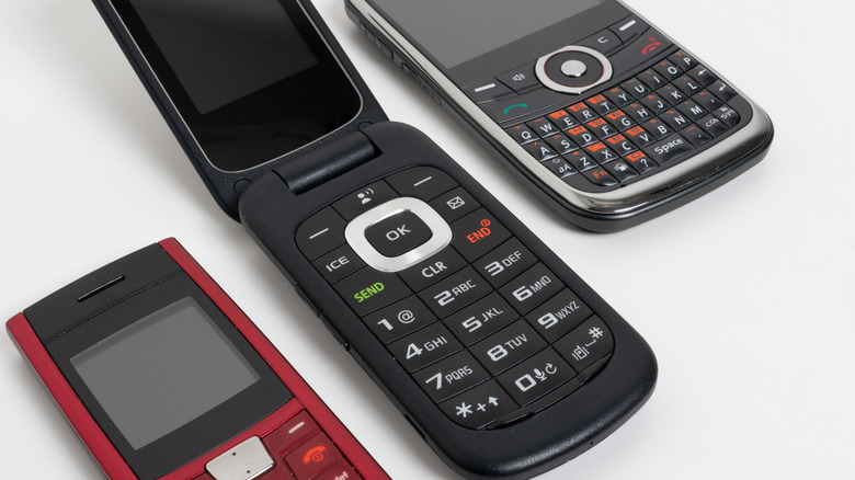 The mobile phones from the 1990s, including a flip phone and a Blackberry, on a white background